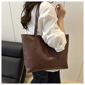 Detail view of dark brown tote bag with premium crocodile texture leather on model