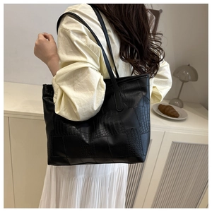 Detail view of the black crocodile embossed faux leather tote bag in a modern room setting