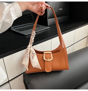Dettaglio borsa baguette marrone effetto coccodrillo con fibbia dorata e foulard di seta