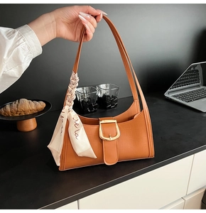 Détail du sac à bandoulière marron motif croco avec foulard en soie et boucle dorée