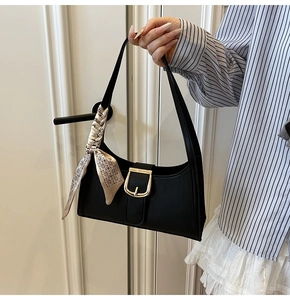 Détail du sac à bandoulière noir texture crocodile avec boucle dorée et foulard en soie