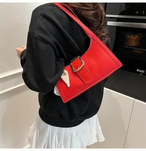 Détail du sac à bandoulière rouge avec gaufrage crocodile et grande boucle en métal doré