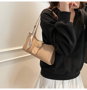 Détail du sac baguette beige motif crocodile avec boucle dorée et foulard en soie décoratif