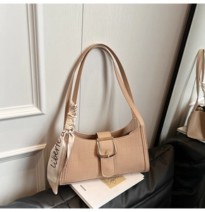 Détail d'un sac sous le bras en similicuir crocodile beige avec foulard et boucle dorée