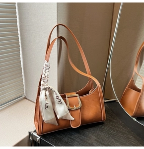 Détail du sac à main en cuir croco avec boucle fer à cheval dorée et foulard en soie