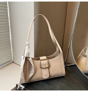 Détail du sac baguette beige avec relief croco, boucle dorée et foulard en soie à motifs