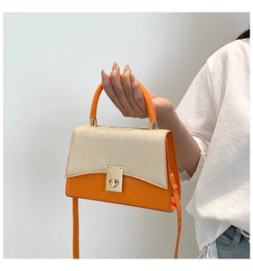 Détail du sac à main en cuir orange avec rabat tissé beige et fermoir rotatif doré