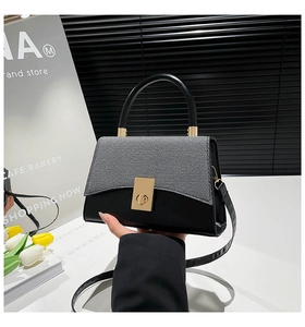 Détail du sac bandoulière bicolore avec fermoir métallique doré et texture tissée