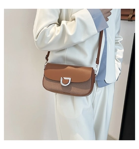 Detail of a brown leather and fabric crossbody bag with silver D-buckle on white suit