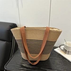 Woven straw tote bag with black stripes and brown canvas handles for summer beach style