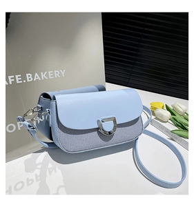 Detail of light blue crossbody bag with striped fabric panel and silver D-ring buckle