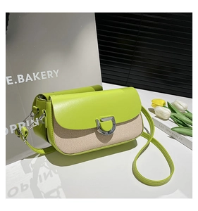 Detail of green leather flap and beige striped woven texture on a stylish crossbody bag
