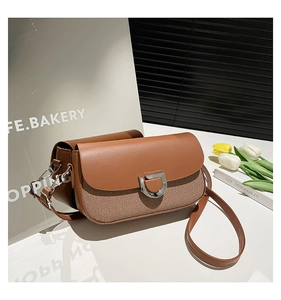Detail of a brown leather and woven fabric crossbody bag with silver D-ring buckle closure