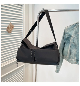 Close-up of black multifunctional crossbody gym bag with dual zipper pockets on a hanger