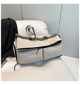 Detail view of khaki canvas duffel bag featuring large front pockets on white sofa