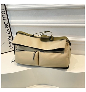 Detail of beige utility messenger bag with olive green wide strap and dual front pockets
