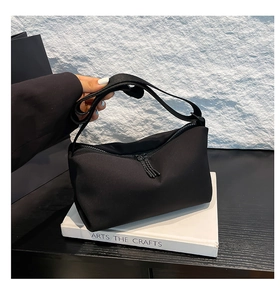 Detailaufnahme der schwarzen Nylon-Umhängetasche mit Quasten und breitem Schultergurt