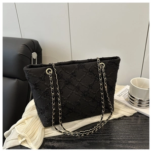 Detail of black quilted tote bag with gold chain strap and textured fabric with sequins