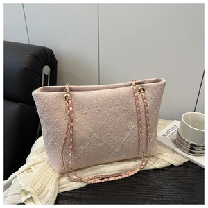 Detail of pink quilted tote bag with textured fabric, bow patterns and gold chain straps