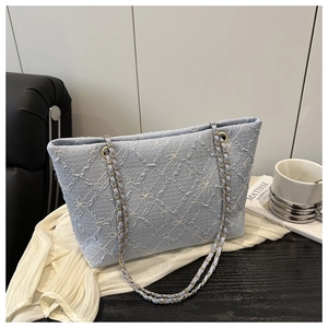 Detail of light blue tote bag with floral quilted fabric and chain straps in aesthetic setting