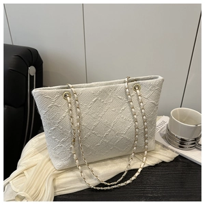 Detailed macro view of white jacquard fabric texture and woven gold metal chain strap