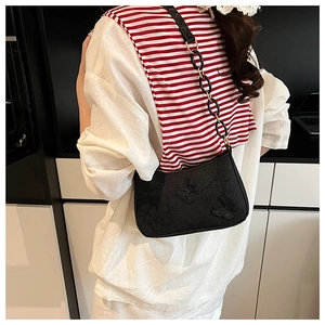 Detail of black underarm tote bag featuring butterfly embroidery and chain strap