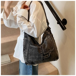 Detail of vintage washed black denim tote bag with functional exterior pockets on model