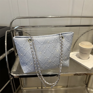 Stylish light blue floral embroidered tote bag with a golden chain strap on a display stand