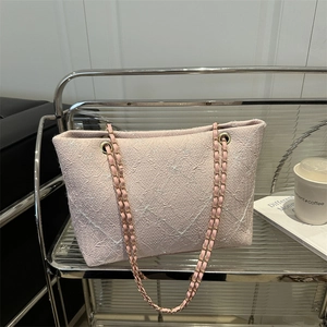 Pink tweed tote bag with gold chain strap and diamond pattern in modern setting