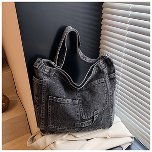 Detail of black vintage denim hobo bag featuring large front pockets and wash texture