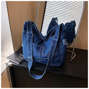 Detail of blue denim tote bag showing distressed edges and silver metal buckle