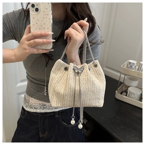 Detail of woven straw bucket bag with silver butterfly clasp and pearl drawstring