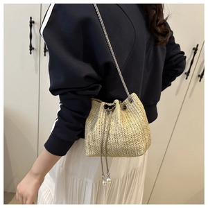 Detail of woven straw bucket bag with silver chain strap and pearl drawstring closure