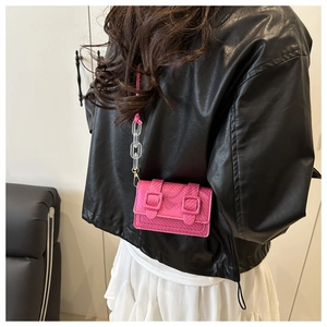 Detail of fuchsia mini square bag with acrylic chain worn on a black leather jacket