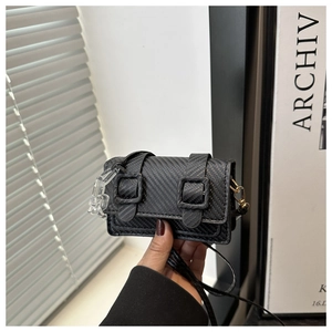 Detail of black mini crossbody bag with twill texture and decorative double strap buckle