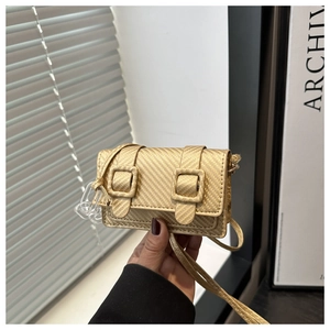 Detail of a gold mini crossbody bag with carbon fiber texture and acrylic chain accent