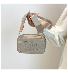 Detail of glitter camera bag with SM rivet studs and wide beige textile strap
