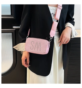 Detail of pink sequin camera bag with silver rivet letters and wide strap on a blazer