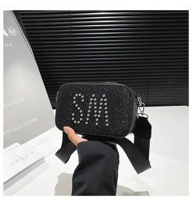 Detail of black sequin camera bag with silver rivet SM letters and wide nylon strap