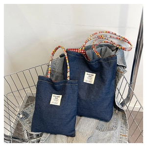 Vista dettagliata delle borse in denim con manici intrecciati e etichette in tela