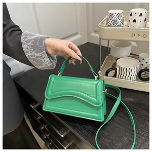 Detail of green leather handbag featuring unique wavy texture and slim shoulder strap