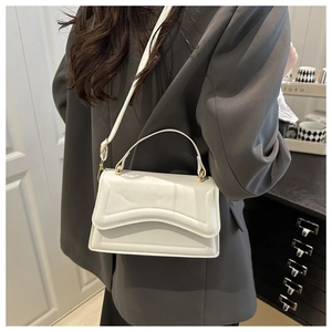 Detail of white leather crossbody bag with geometric embossed pattern and gold hardware