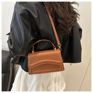 Brown leather crossbody bag with wave texture shown on a model in a street style view