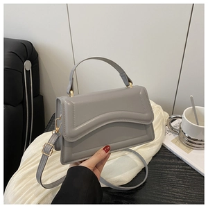 Close-up of gray leather handbag with wavy stitching and premium gold metal hardware