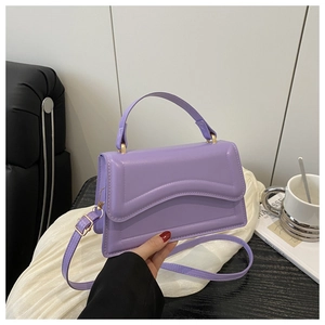 Detail of taro purple textured handbag with curved embossing and gold-tone hardware