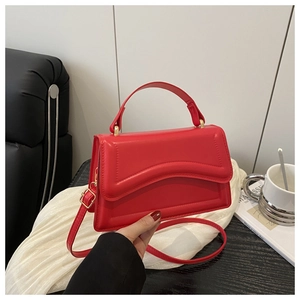 Detail of red PU leather bag featuring wave embossing and adjustable shoulder strap