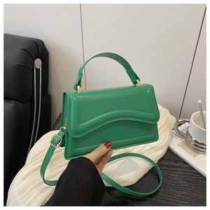 Detail of vibrant green PU leather crossbody bag with elegant wavy stitching and metal buckle