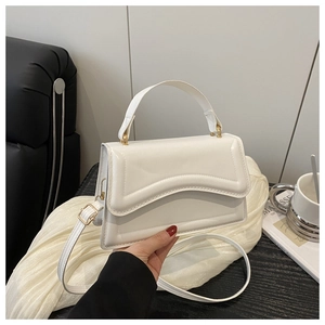 Detail of minimalist white leather handbag with golden hardware and round top handle