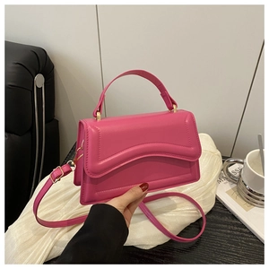 Detail of rose pink leather handbag featuring a unique wavy layered flap and gold hardware