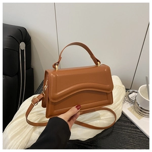 Detail of caramel brown leather crossbody bag with wavy quilted flap and gold hardware